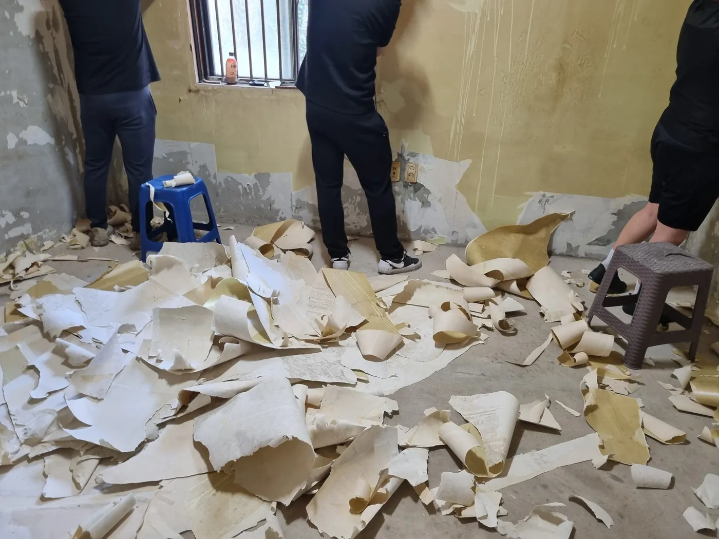 작업자들이 벽지를 한 장씩 떼어내는 담배 냄새 제거 현장